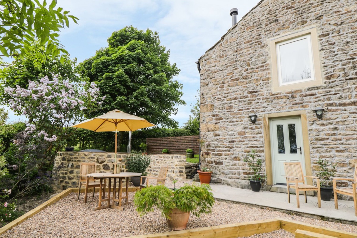 Shawclough Barn stone exterior with patio table and parasol