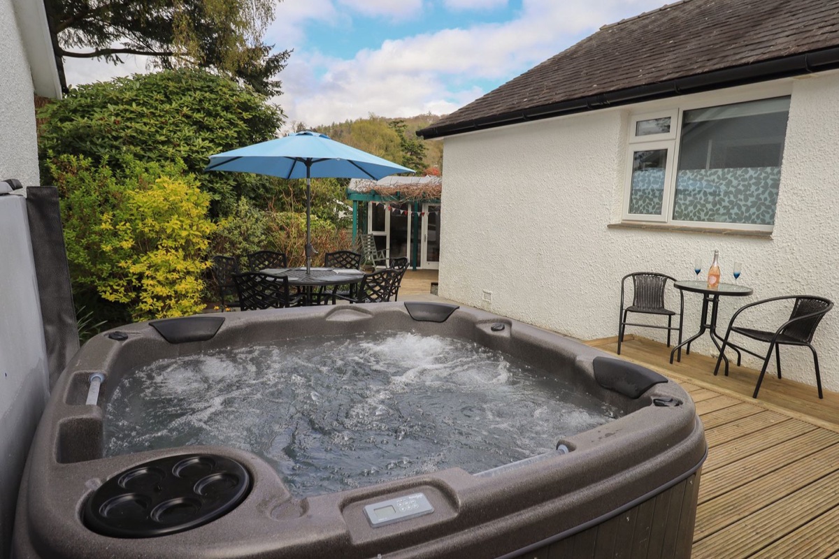 Bubbling hot tub on the deck with garden and Lakeland hills at Silver Birches