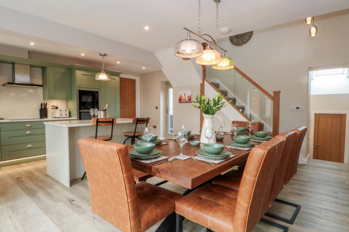 Open-plan kitchen and dining area with island and leather chairs at Small Lane Barn