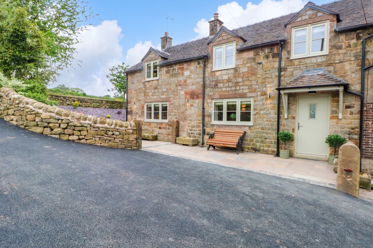 Stone cottage with cream windows, green front door and dry-stone wall at Small Lane Cottage