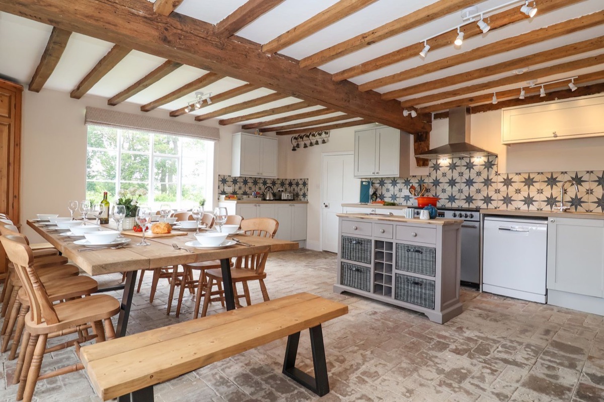 Beamed kitchen and a long dining table set for a group at South Grange House
