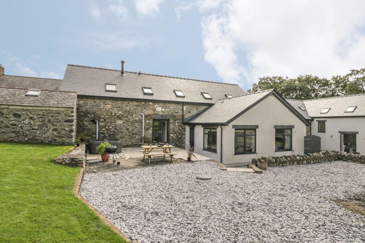 Storws stone cottage exterior with lawn and gravel courtyard