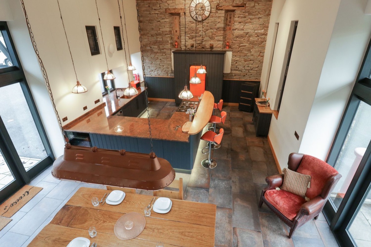 Kitchen from the mezzanine with stone wall and copper pendant lights at The Barn at Sunny Barn