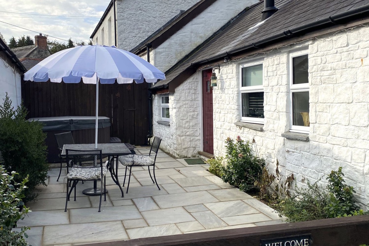 Patio seating and hot tub beside the stone cottage at The Barn at Waunlippa