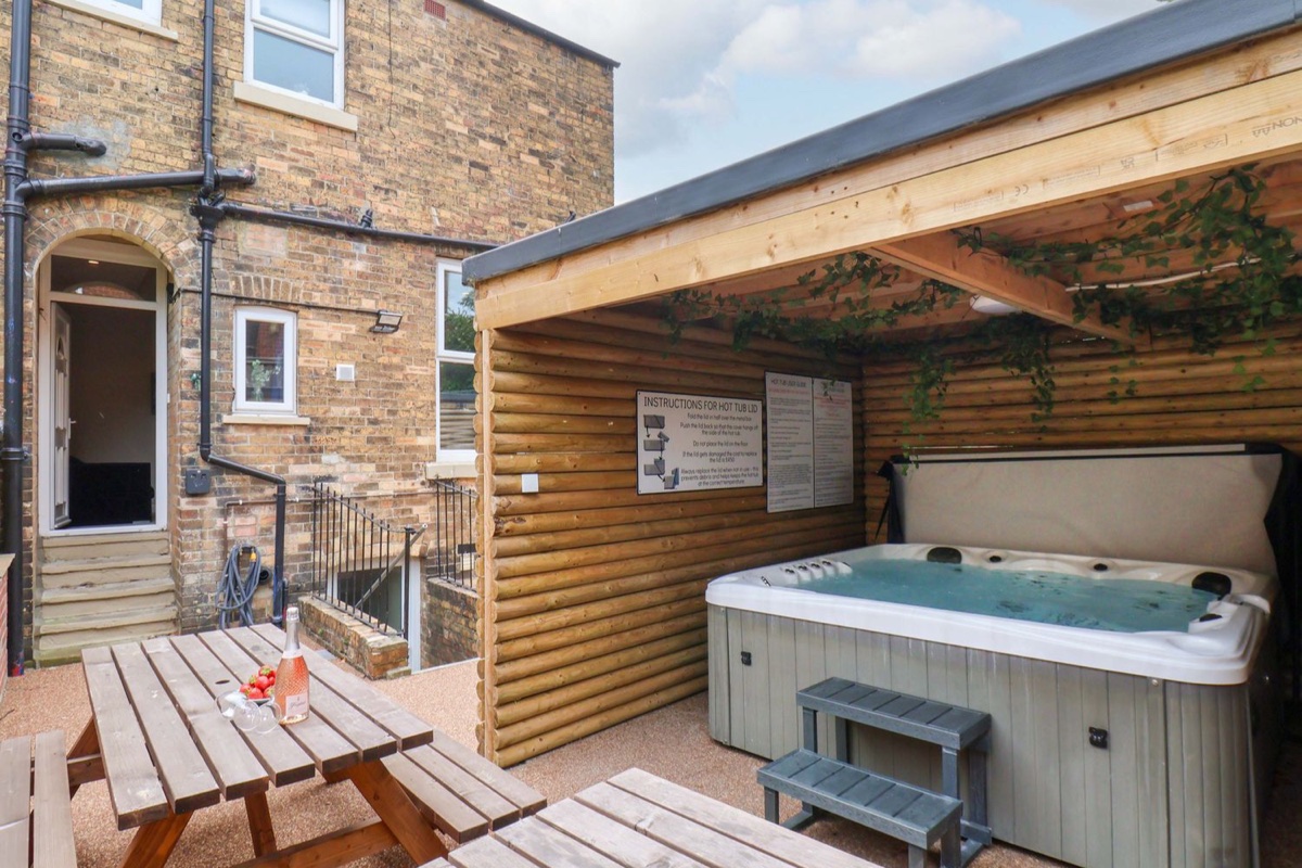The Corner House covered hot tub beside outdoor dining and brick walls