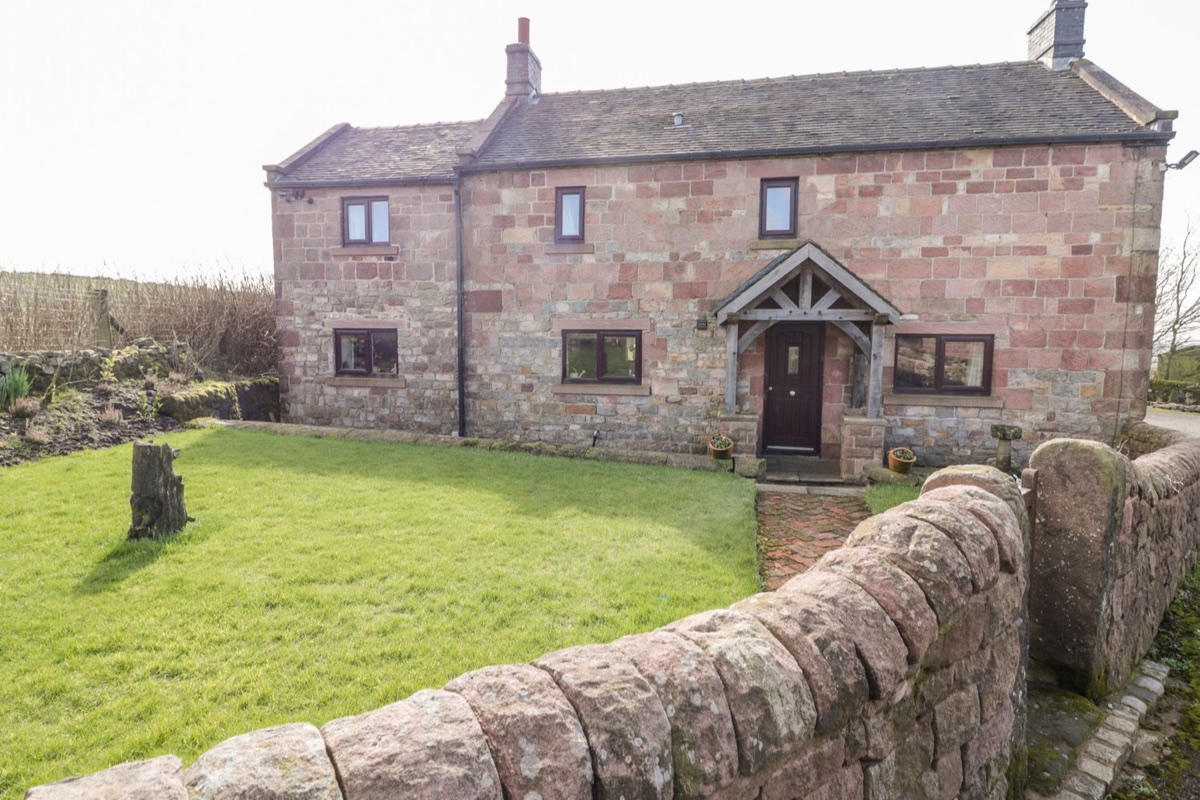 Red-sandstone farmhouse with oak porch and dry-stone wall at The Farmhouse, Biddulph Moor