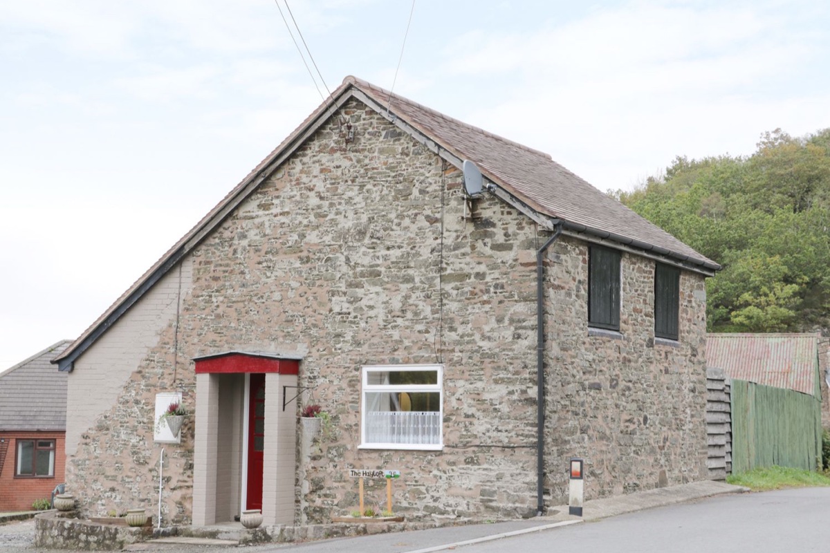 The Hayloft stone exterior with red door under pale sky