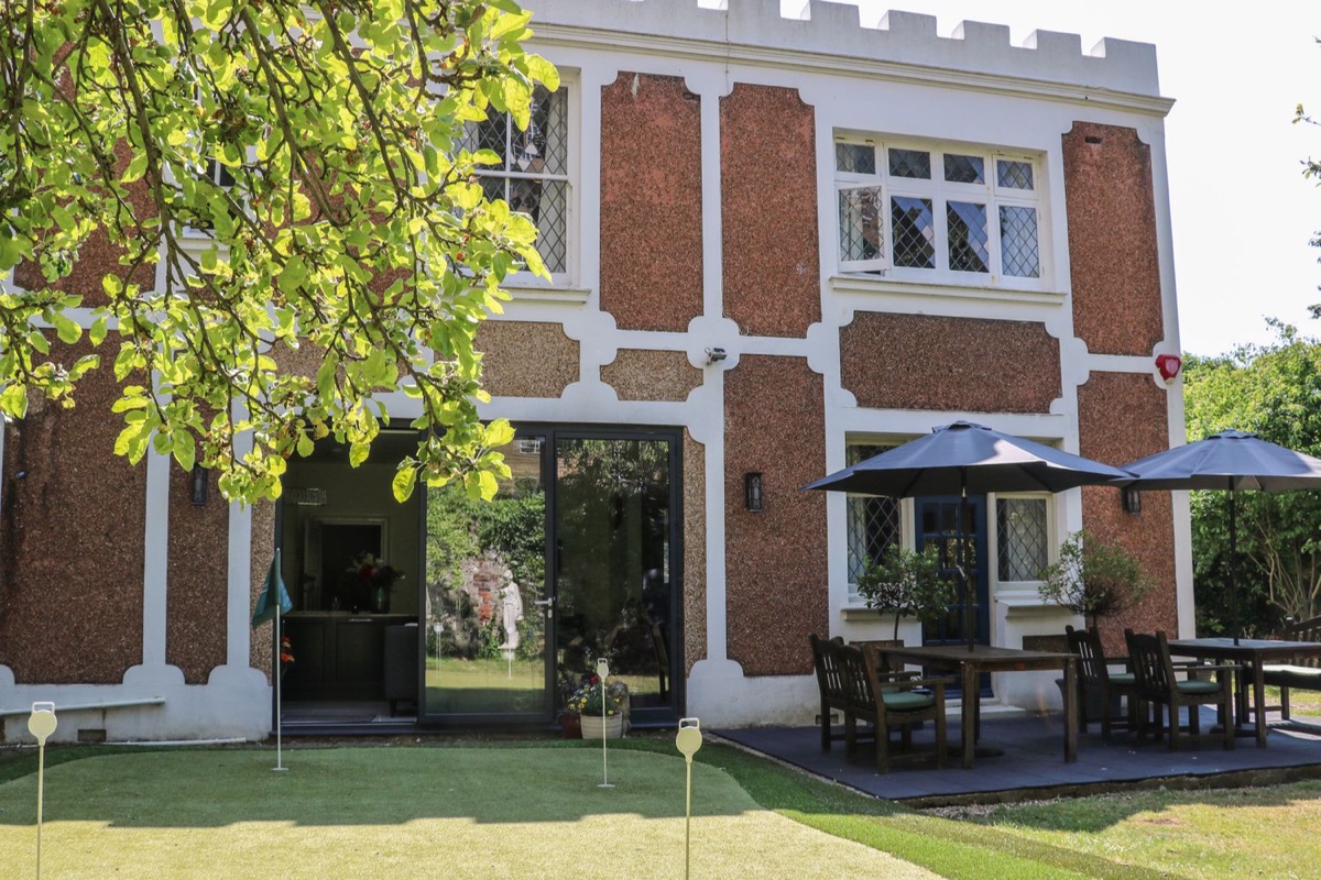 The Hideaway, a castellated rendered house with a garden putting green in Hove