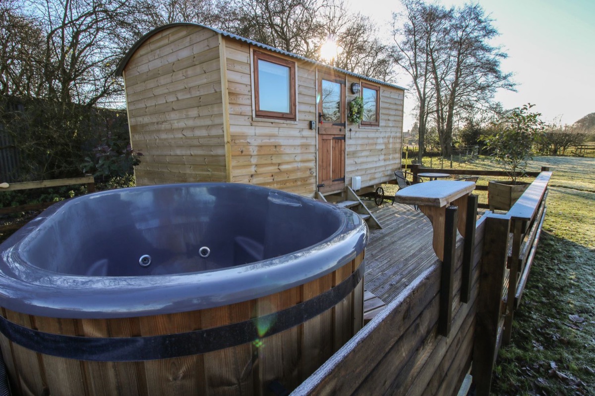 The Oak Hut beside its hot tub on a frosty deck in open countryside