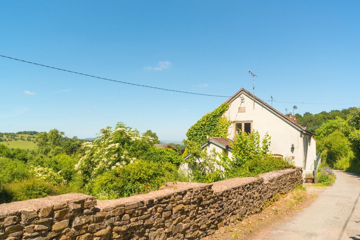 The Old Chapel exterior with stone wall and valley countryside behind