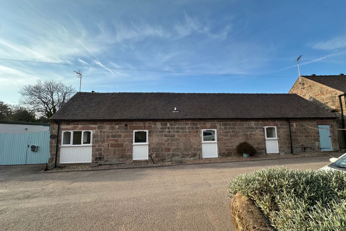 Single-storey stone barn conversion with white doors at The Old Parlour, Alton