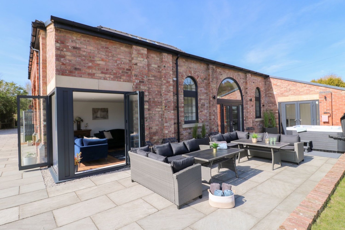 The Old Pump House brick exterior with patio seating and hot tub