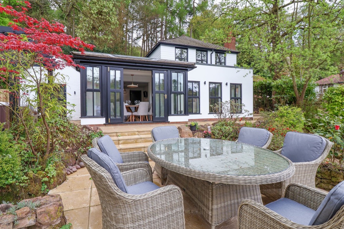 White house with bifold doors and a garden patio with rattan seating at The Sheiling
