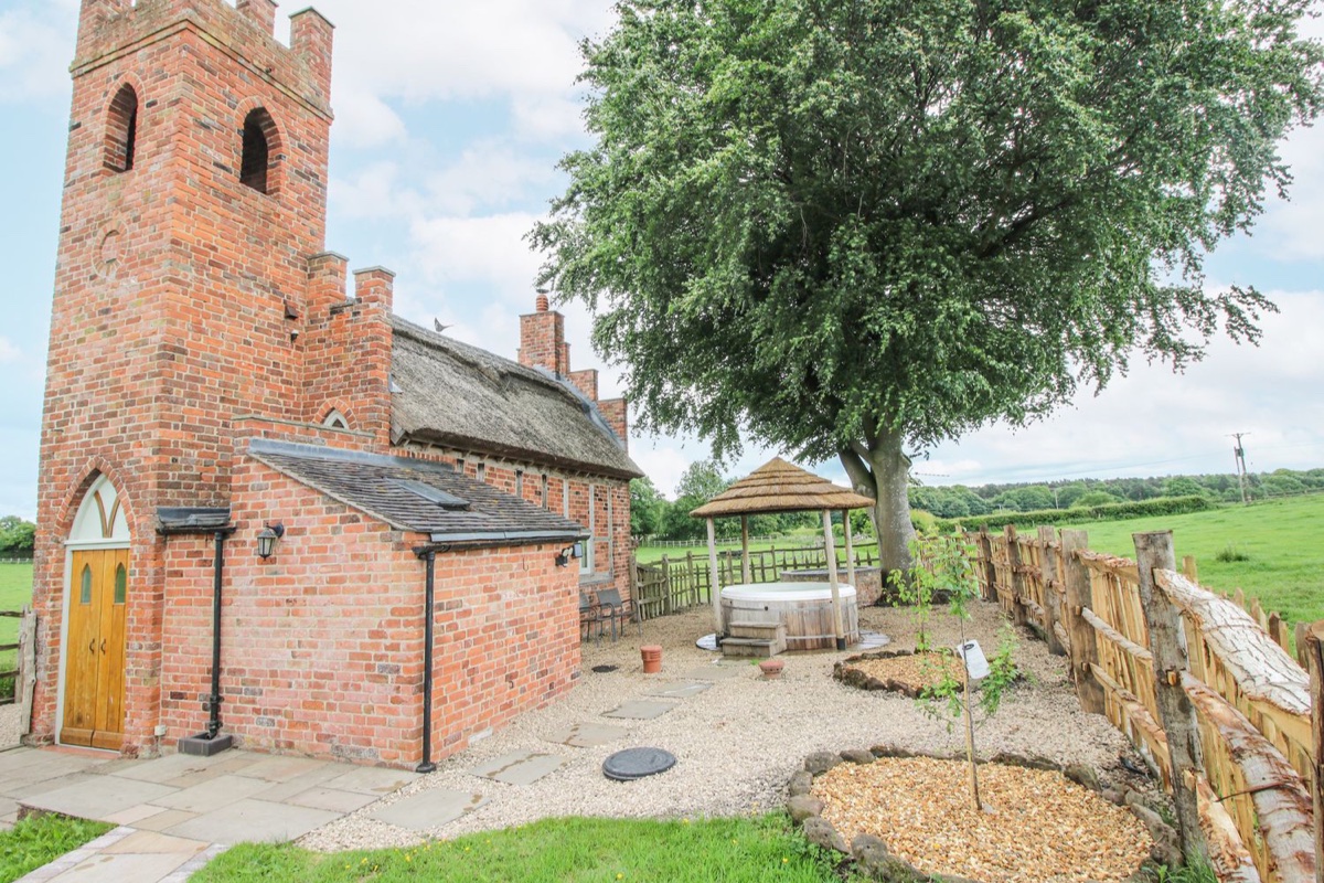 The Shooting Folly brick exterior with covered hot tub beside open fields