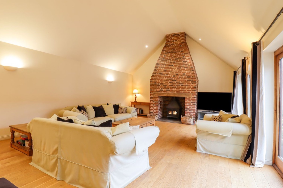 Beamed living room with a brick fireplace at The Stables at Hall Barn