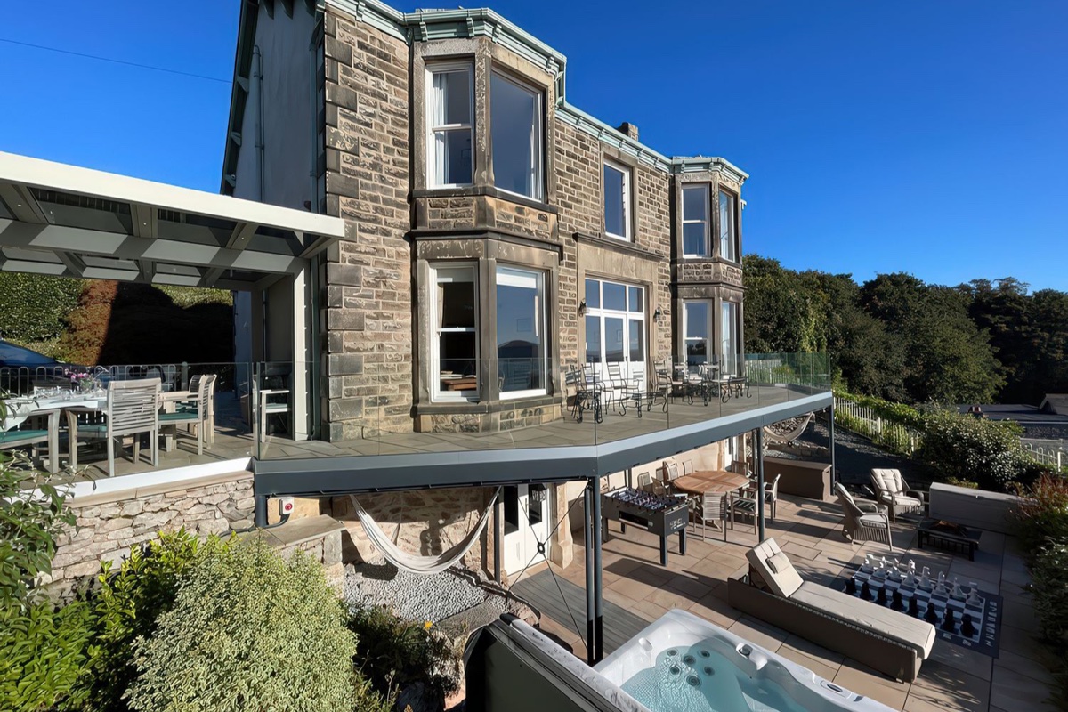 Imposing Victorian house with multi-level terraced garden, stone steps, and hot tub below