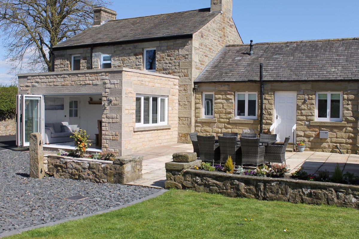 Vine Cottage stone exterior with patio furniture and lawn