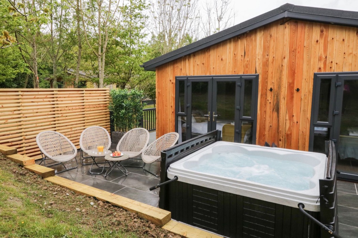 Hot tub beside the cedar lodge with outdoor seating at Watch Tree Lodge