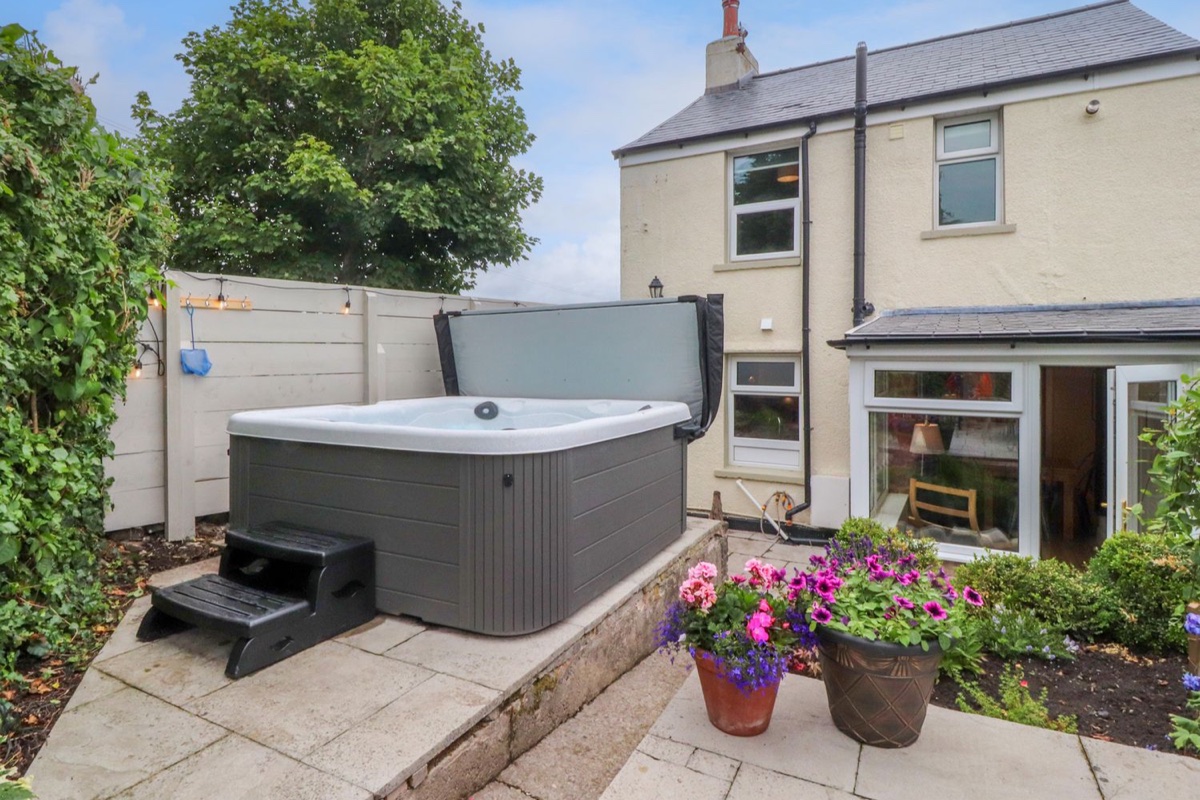 Woodman Cottage garden with hot tub, potted flowers and rear doors