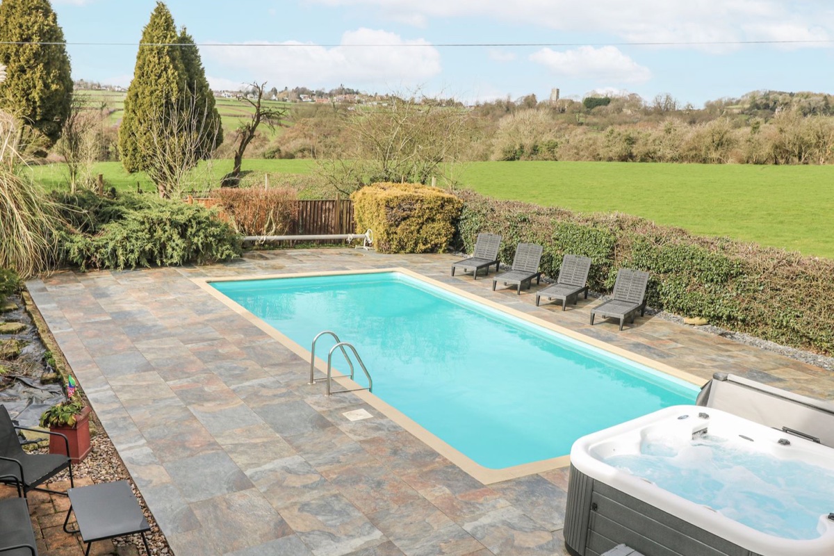 Woodpit Cottage pool and hot tub terrace with countryside beyond