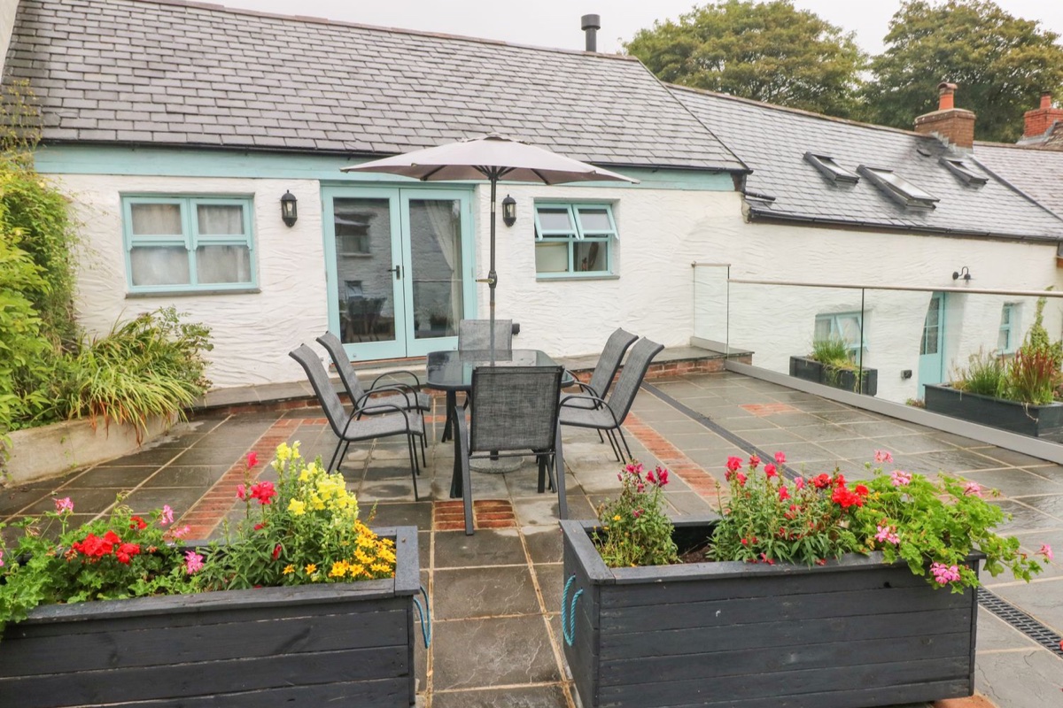 Y Beudy patio with dining set and the blue-door cottage behind in Crosswell