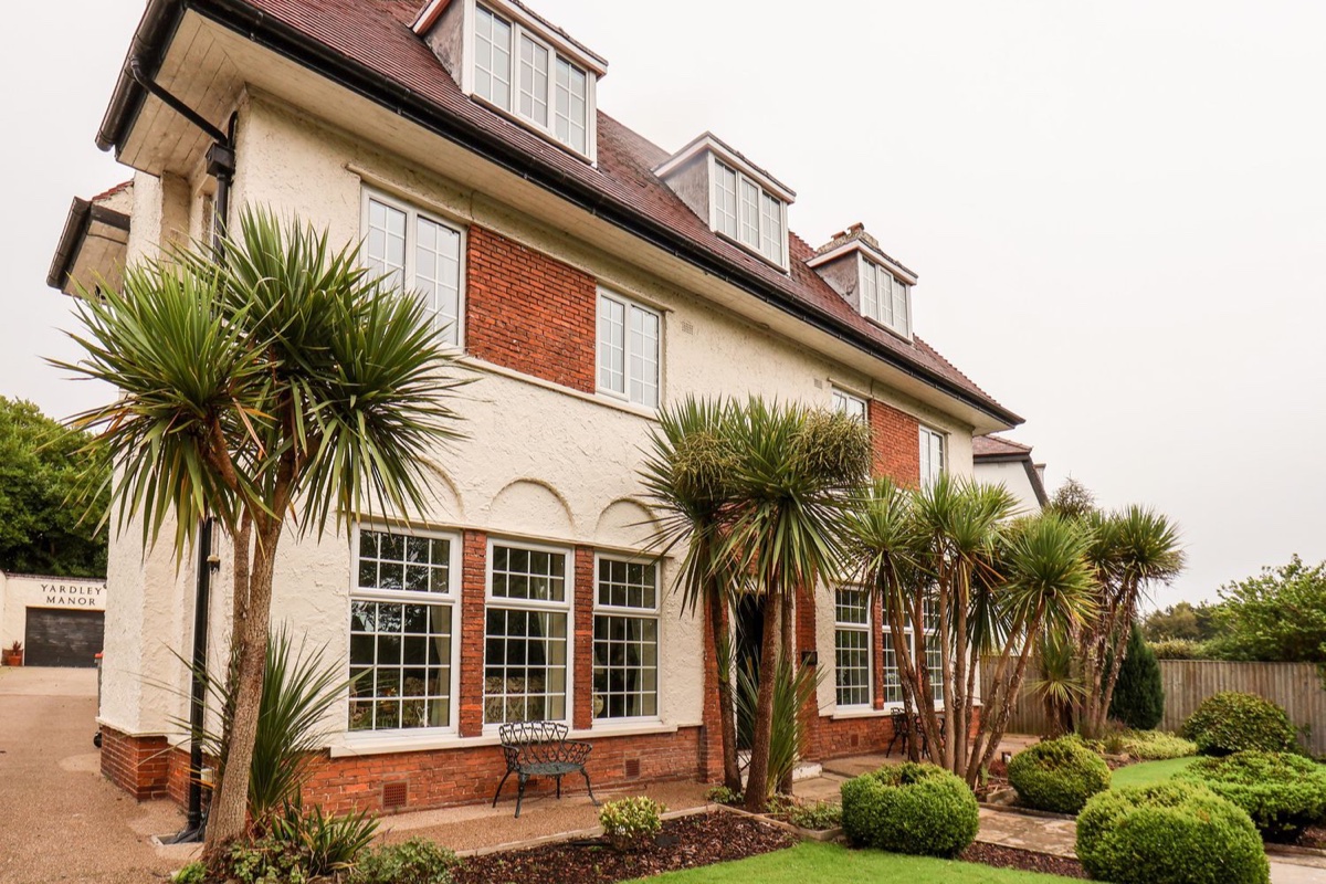 Yardley Manor garden-side exterior with palms and tall windows